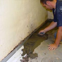 A basement waterproofer installing a perimeter drain system in Woodstock
